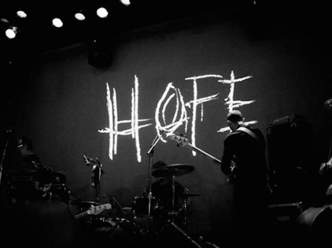 Image of Godspeed You! Black Emperor onstage with the word HOPE projected behind them